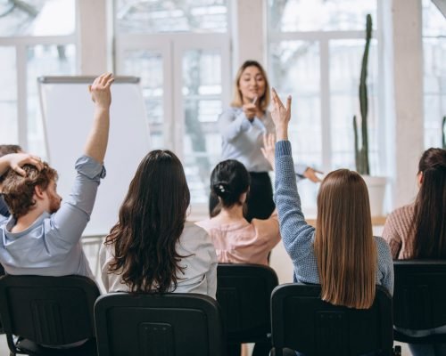 Increase. Female speaker giving presentation in hall at university workshop. Audience or conference hall. Rear view of unrecognized participants. Scientific, business event, training. Education